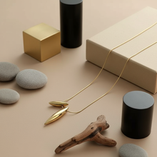 Dual Drop Pendant on a beige surface with rocks, a box, and cylindrical objects.