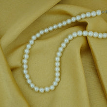 Pearl necklace on a textured beige fabric background