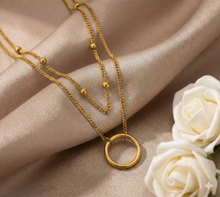 Gold Plated Layered Ring Pendant on beige fabric with white roses.