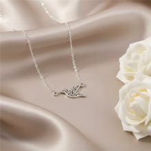 Silver Plated hummingbird pendant necklace on smooth beige satin with white roses nearby