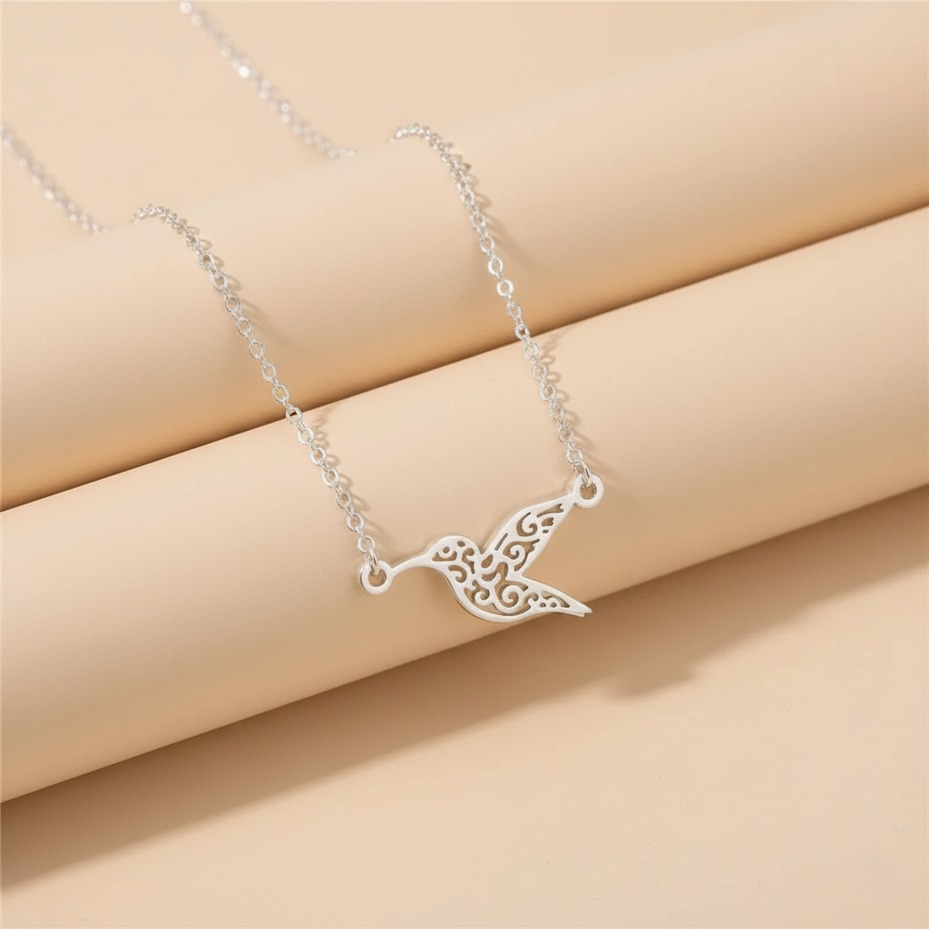 Silver hummingbird pendant necklace displayed on beige background highlighting fine details